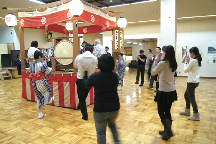 ▲祭典實際上會在室外舉行，從正中央名為「屋型」的高台傳出樂聲，民眾也隨之起舞。　圖：向日遊╱提供