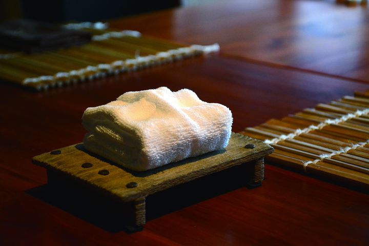 ▲供顧客使用的毛巾摺捏成豆腐狀外，連質感如木作的底盤，都是經反覆燒製才能呈現。　圖：渡小月／提供