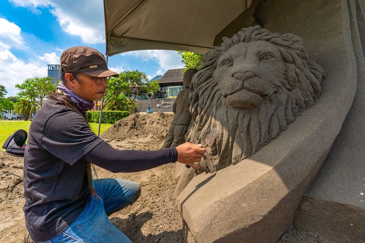 ▲「2022八里城市沙雕展」沙雕師們正投入雕刻創作中，這是將從沙雕中跳出的生動獅子。　圖：新北市政府觀光旅遊局／提供