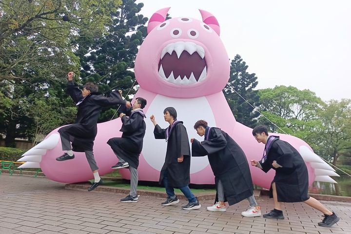 畢業生在外星獸氣球裝置前搞怪拍起人類進化史過程。　圖：六福村主題遊樂園／提供