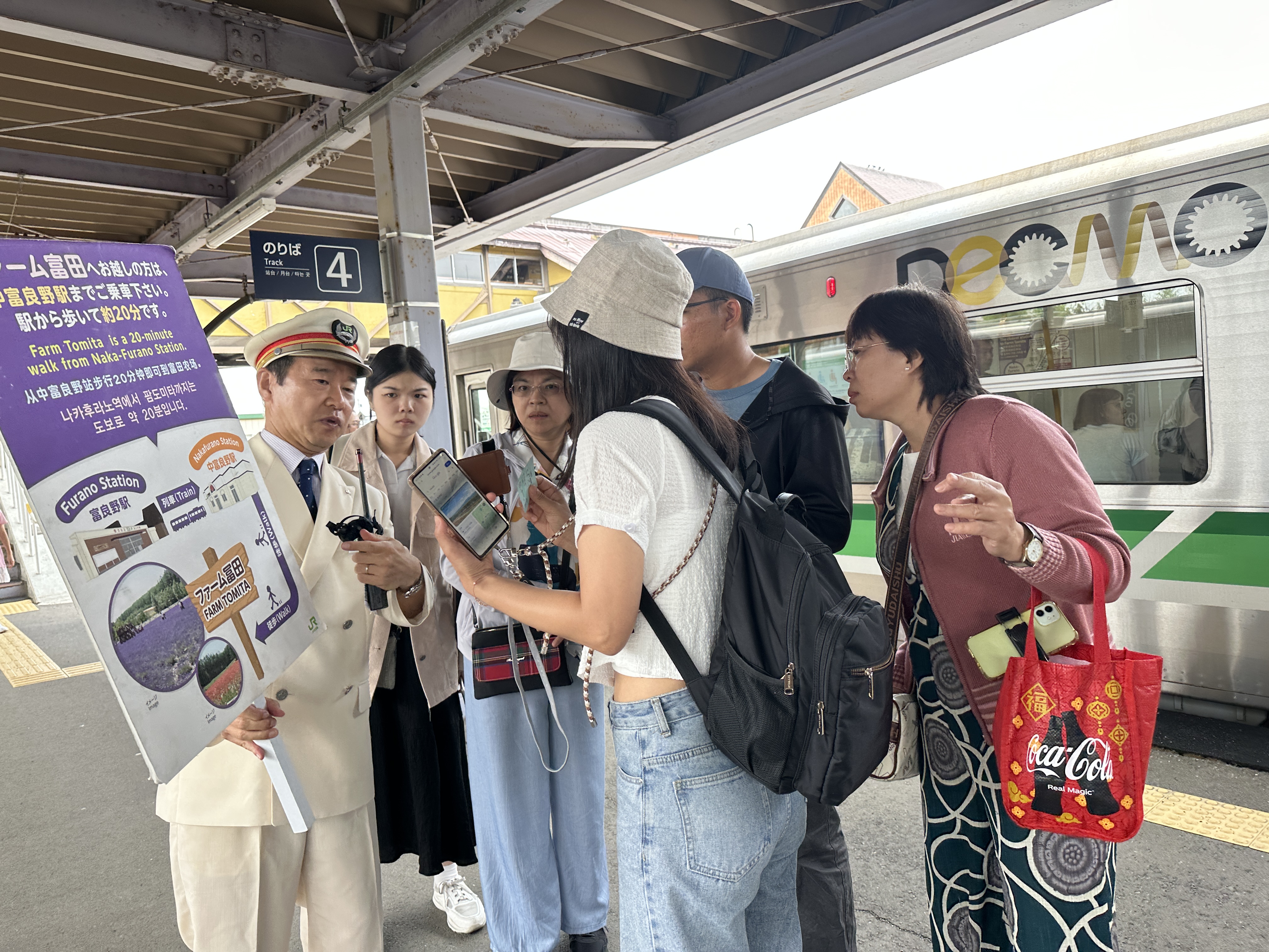 ▲富良野站長平澤信在月台上拿著大看板為海內外旅客解惑。　圖：蔡雅雯／拍攝