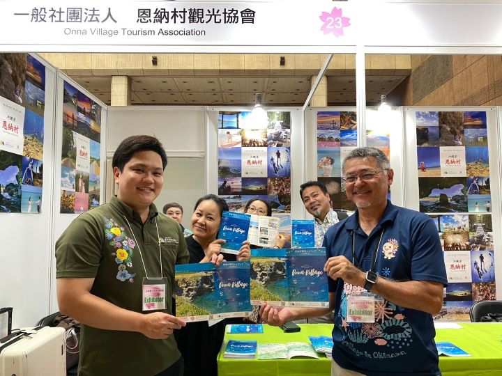 ▲（右）恩納村役場商工觀光課課長介紹，恩納村是面海村落，聚集許多大型度假飯店，也可體驗許多海上活動，最受歡迎的體驗從彷彿飛行空中的水上飛板。從那霸機場就有接駁巴士可前往恩納村，交通便利。一連三天，攤位上每天11:30、14:00、16:00都有琉球舞蹈演出。　記者-黃千珮／攝