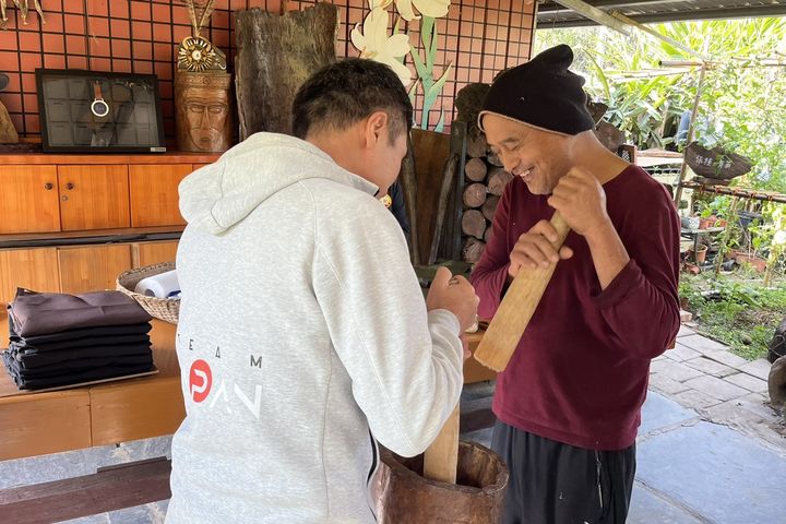 ▲日本 JTB 旅行社臺灣分公司根本克己社長體驗利用傳統杵臼搗花生。　圖：茂林國家風景區管理處／提供 ​