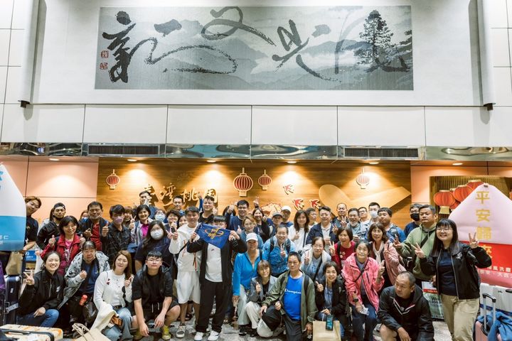 工作人員在機場接機，全部53位團員和2位領隊走出來後開心拍大合照。　圖：何時旅遊／提供