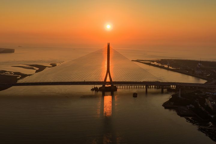 淡水河口的金黃夕照與宏偉的「淡江大橋」巧妙相遇，橋塔的俐落剪影與波光粼粼的水面，勾勒出專屬淡八地區的嶄新觀光地標。　圖：新北市政府觀光旅遊局／提供 