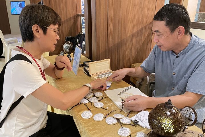 ▲「海南椰雕」省級非物質文化遺產項目代表性傳承人董為勁，在展場指導學員製作椰雕作品。　圖：中華翰維文化推廣協會／提供